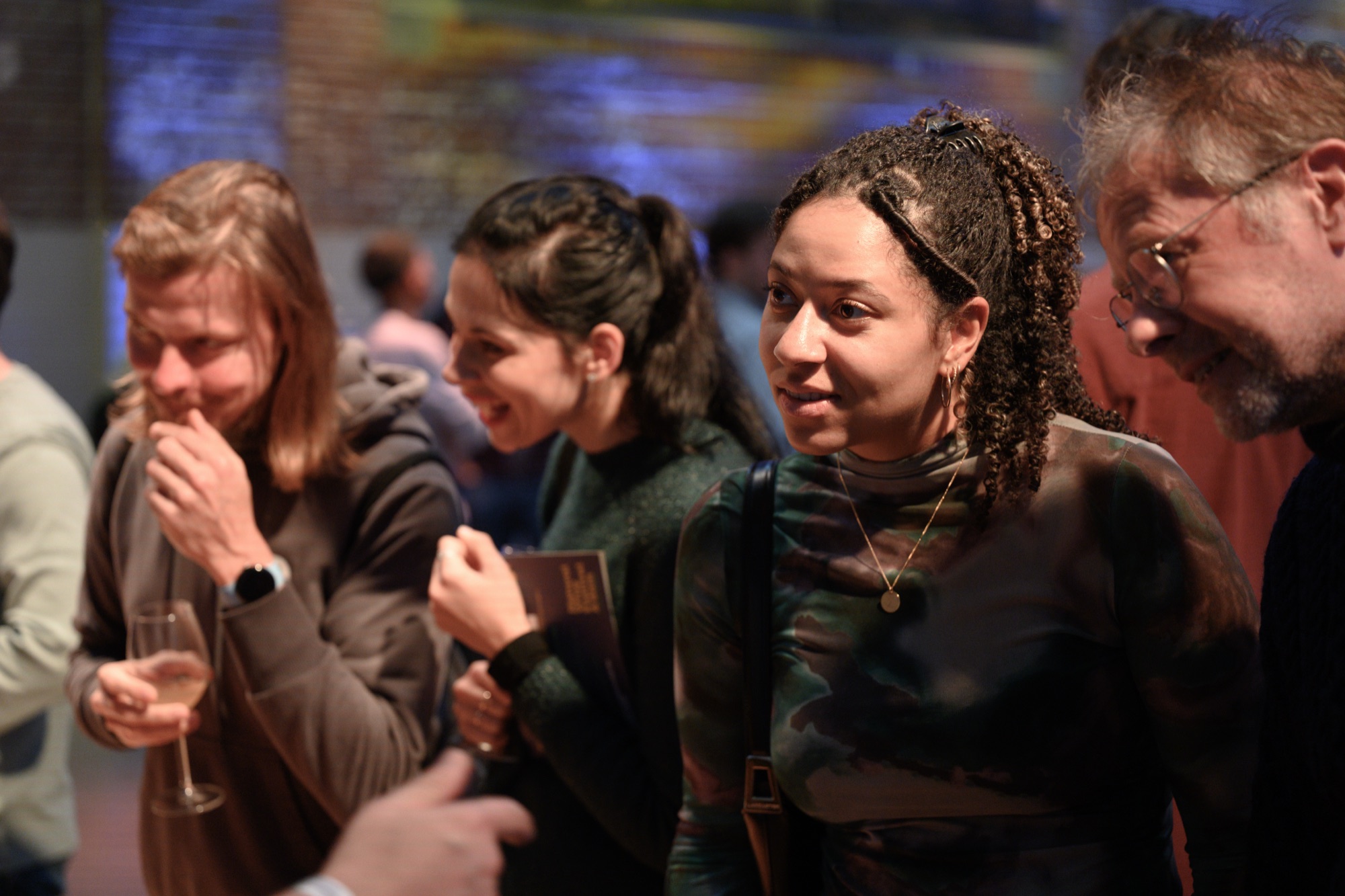 Festival-goers tasting and talking on the floor, one smelling a glass of white wine.